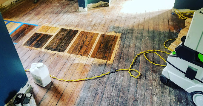 Photo of an old floor with different stain samples added.