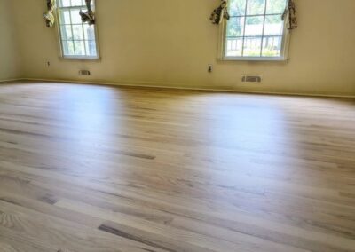 Image of a newly refinished, natuaral wood floor next to sunny windows
