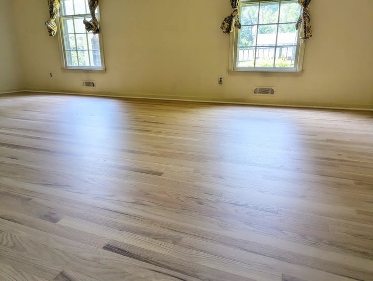 Image of a newly refinished, natuaral wood floor next to sunny windows