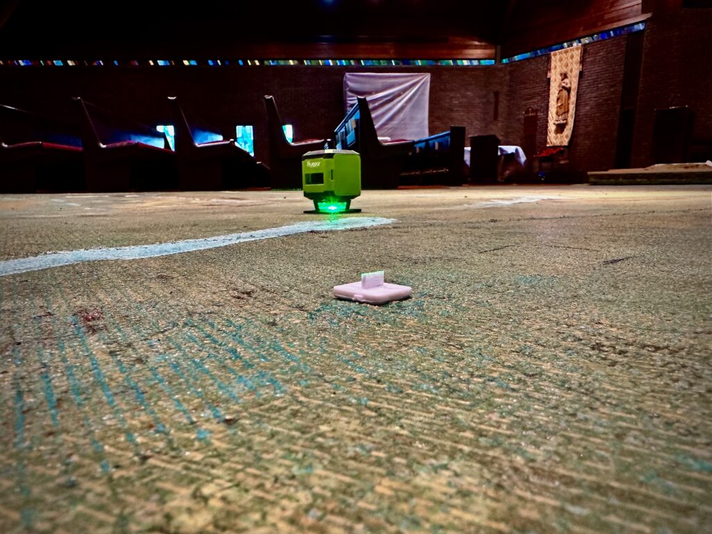 Laser-guided leveling pin used to control self-leveling depth in church sanctuary