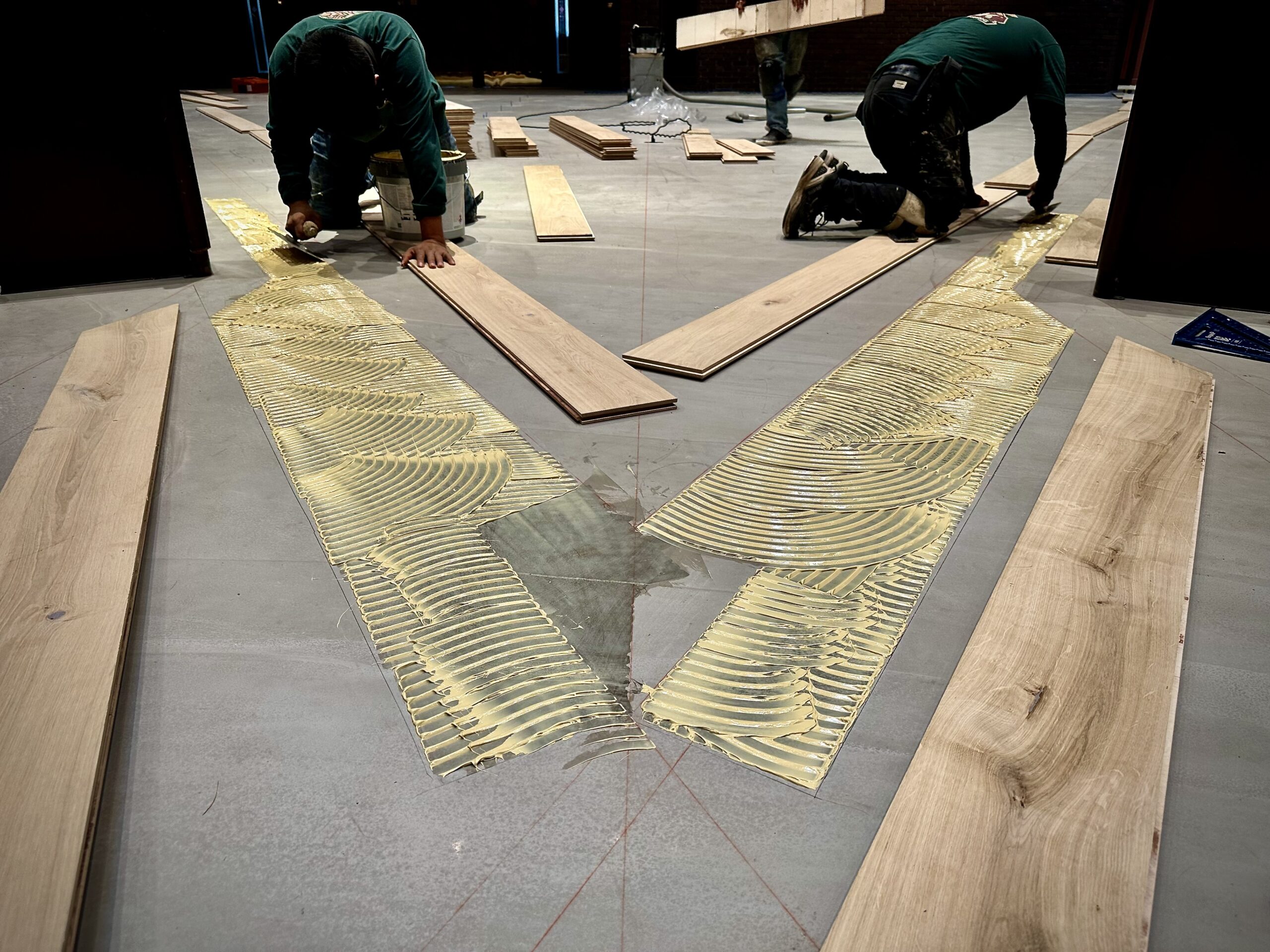 Applying Wakol MS 230 adhesive in precise diamond outlines for the initial European white oak plank installation