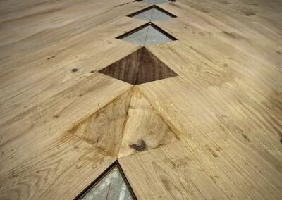 First walnut and European white oak diamond inlays installed within the field flooring, with remaining diamond locations left open