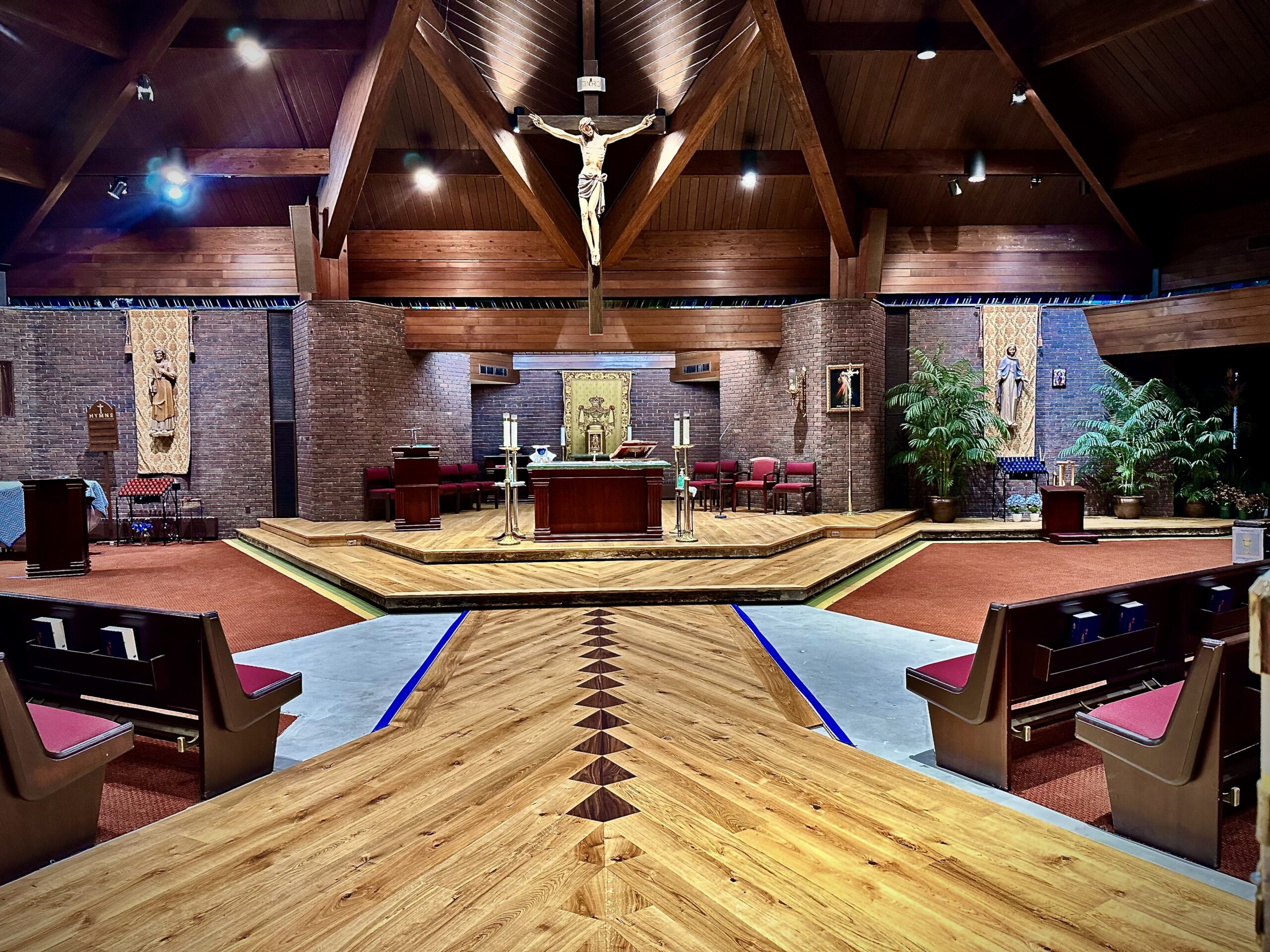 Twelve walnut diamond inlays in a wide plank European oak floor pointing toward the altar at Saint Thomas More Church