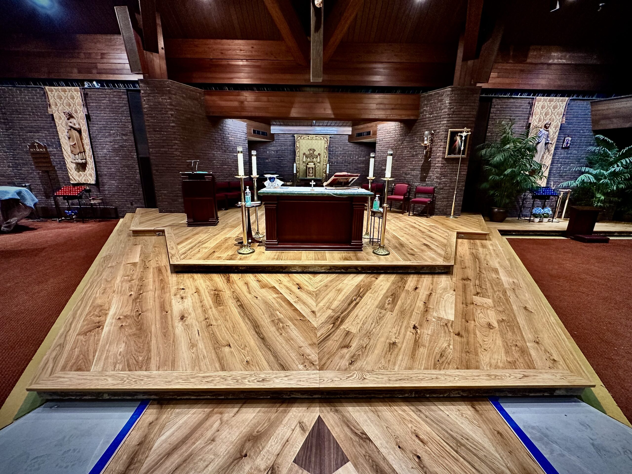 Wide plank European oak floor layout on the first altar platform showing mitered chevron where left and right plank fields meet at Saint Thomas More Church
