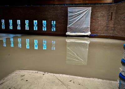 Self-leveling compound freshly poured along left side of sanctuary