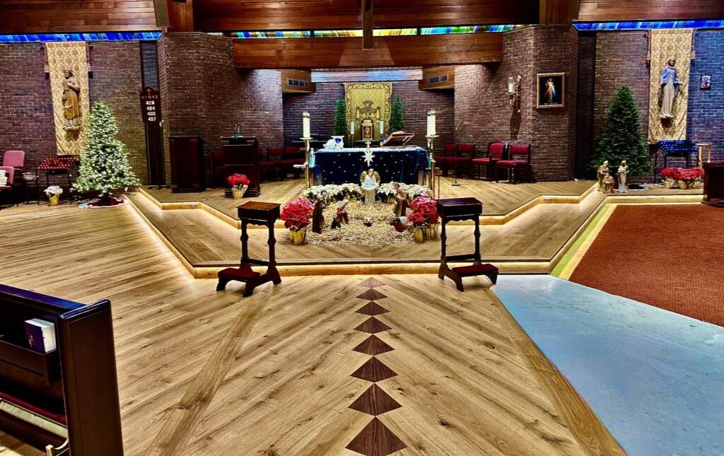 Finished European white oak wide plank floor with walnut diamond inlays, altar platforms, and LED-lit risers in St. Thomas More Church, Morristown NJ