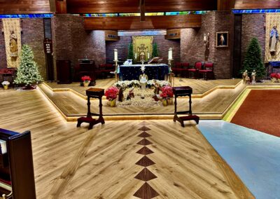 Finished European white oak wide plank floor with walnut diamond inlays, altar platforms, and LED-lit risers in St. Thomas More Church, Morristown NJ