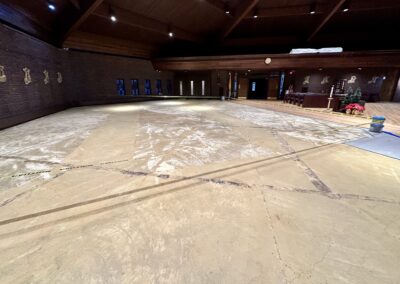 Right side of church sanctuary subfloor exposed with caution tape around pew bolt locations