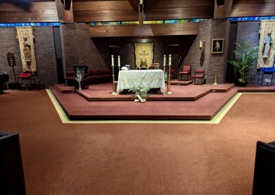 Existing red carpet at the church altar before hardwood floor installation.