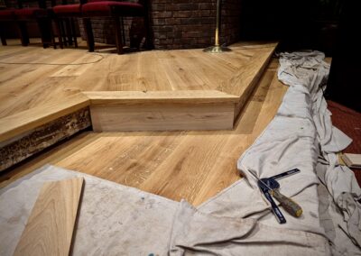 Close-up of a European white oak stair riser being installed on the altar platform at Saint Thomas More Church
